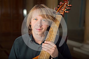 Handsome young musician play viola da gamba in palace photo